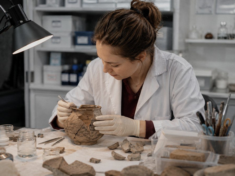 Conservator restoring an ancient ceramic pot in a laboratory
