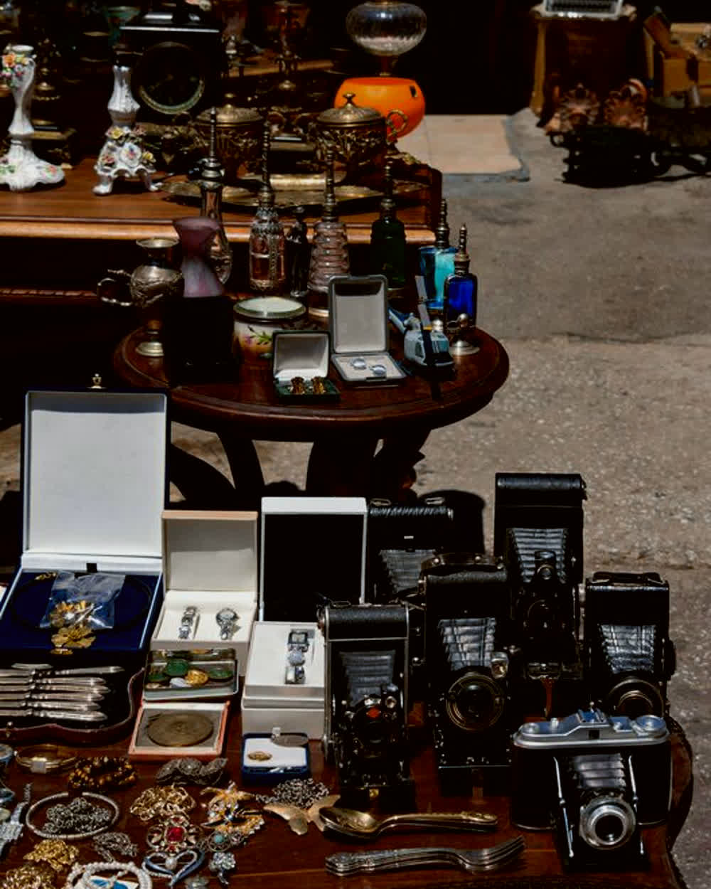 Vintage cameras, jewellery and collectibles laid out on antique tables